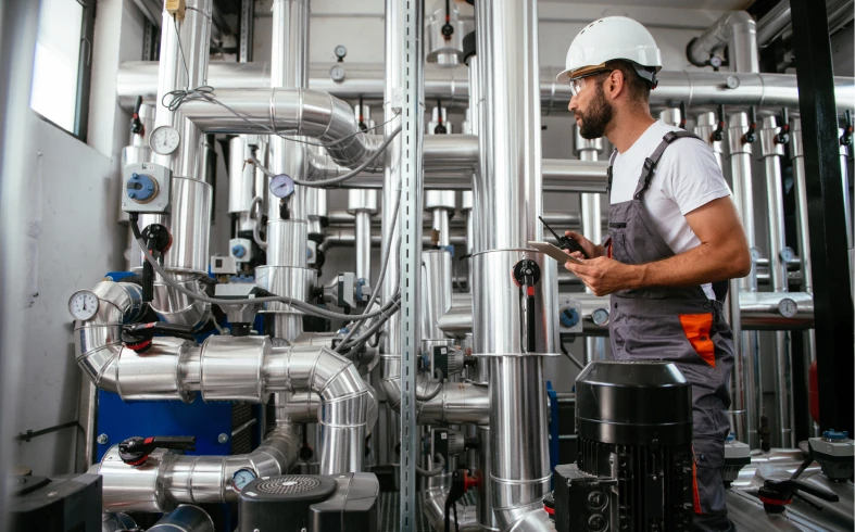 Technician examining machinery in a factory